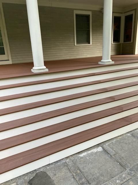 Brown and white wooden steps leading up to a porch with white columns.