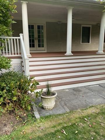 Front porch with steps, white columns, and french doors; a potted plant sits on the patio.