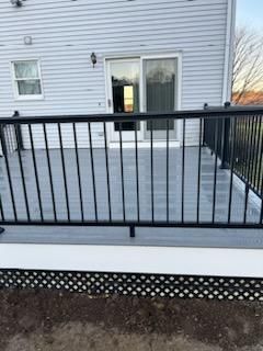 Gray composite deck with black railing and white trim, adjacent to a house with a sliding door.