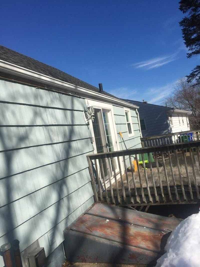Blue house with a deck, sunny day. The deck has a door leading to the house.