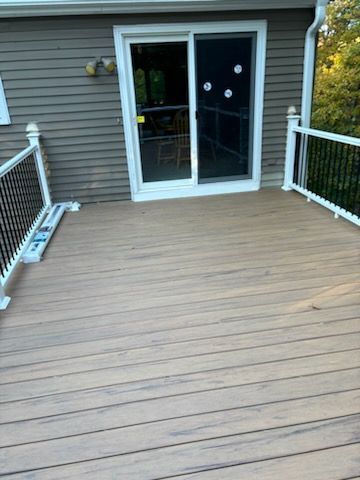Composite deck with sliding glass door and black railing.