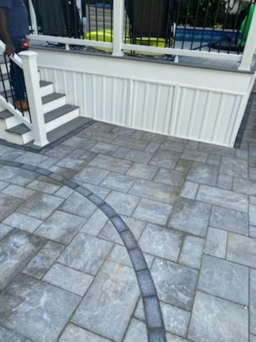 Patio with gray pavers, white deck, and steps; a person stands near the stairs.