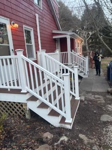 Red house with white porch and stairs; person walks up the steps.