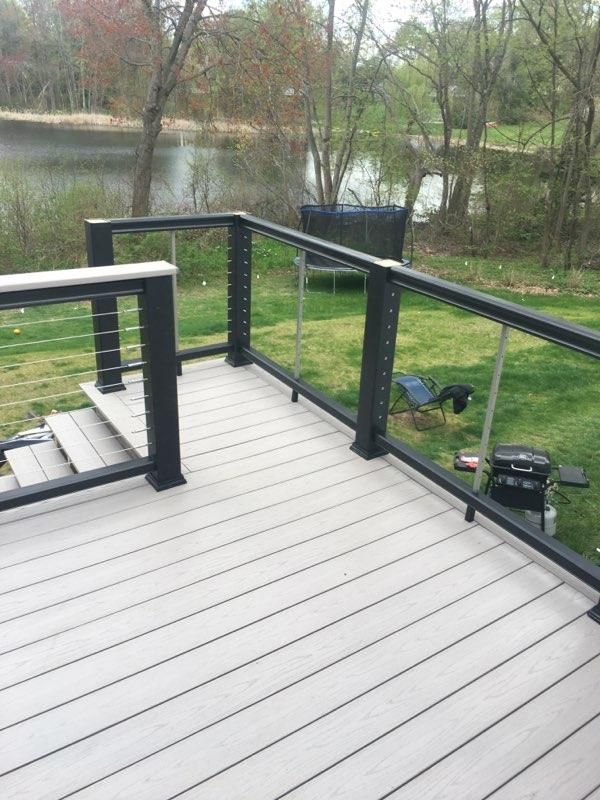 Composite deck with black railing and cable infill, overlooking a pond.