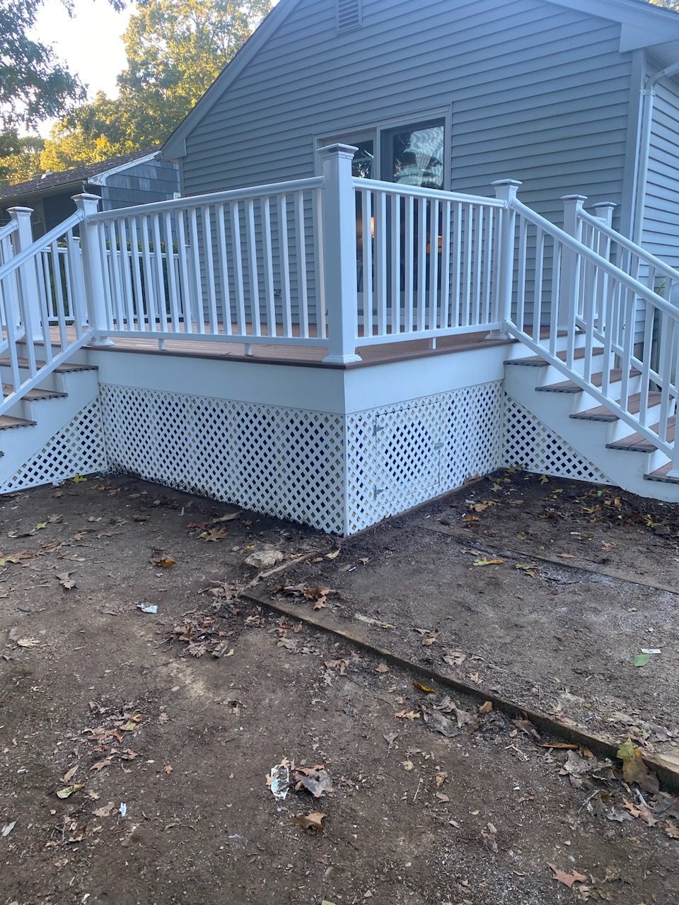 White deck with lattice skirting and steps, set against a light blue house.
