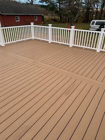 Brown composite deck with white railing in an outdoor setting.