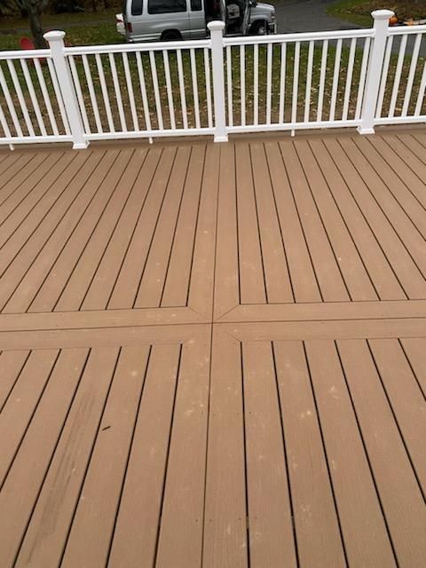 Tan deck with white railing, centered design, vehicle in background.