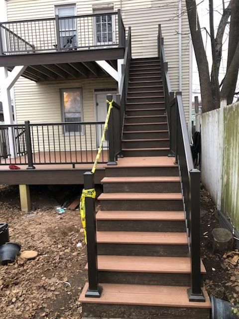 Brown composite deck and stairs with dark railing and posts, leading to a second-story deck.
