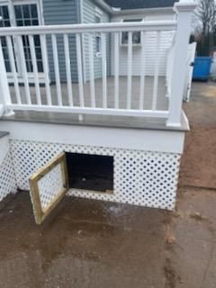 White deck with open storage door framed in wood, latticework below.