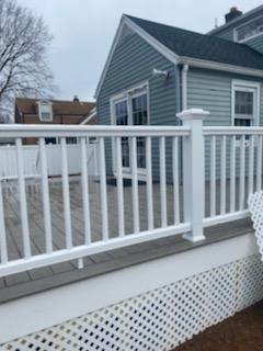 White deck railing with lattice skirting, blue house in background.