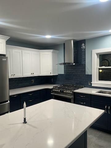 Modern kitchen with white upper cabinets, navy blue lower cabinets, and a white countertop island.