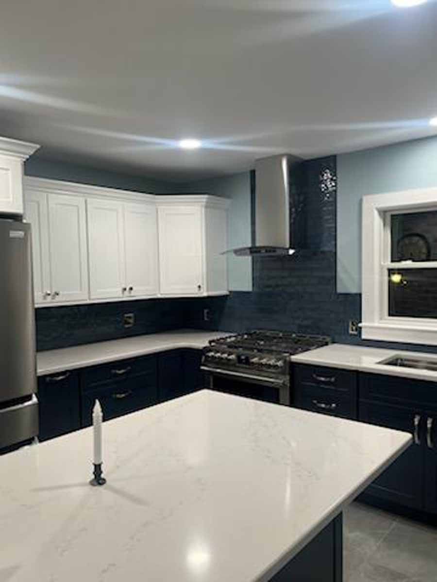 Modern kitchen with white upper cabinets, dark blue lower cabinets, and a white countertop island.