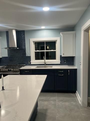 Modern kitchen with blue cabinets, white countertops, and stainless steel appliances.