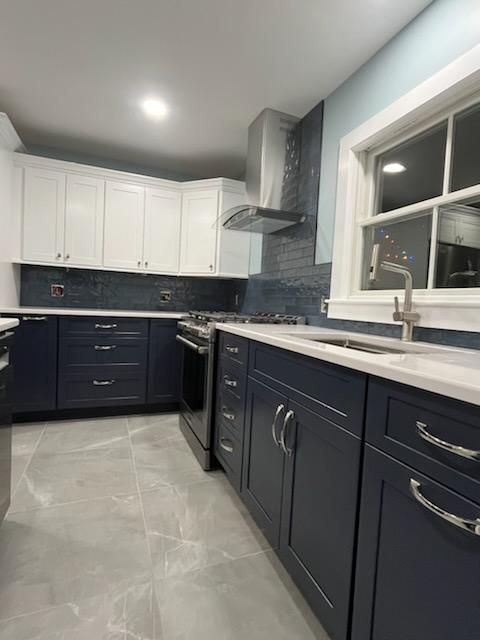 Modern kitchen with white upper cabinets, navy blue lower cabinets, and stainless steel appliances.