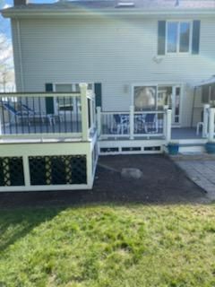 Back of a two-story white house with decks, a sliding glass door, and a partially grass yard.