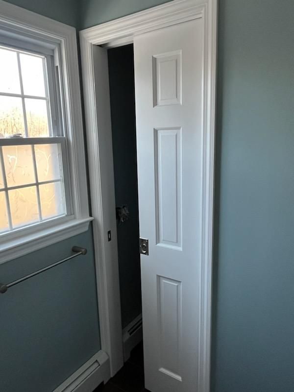 White, paneled pocket door open, revealing a teal-painted room with a window and towel rack.