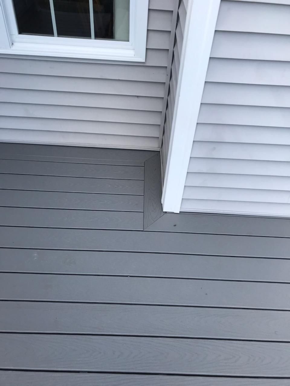 Gray siding and trim detail on a house with a white window.
