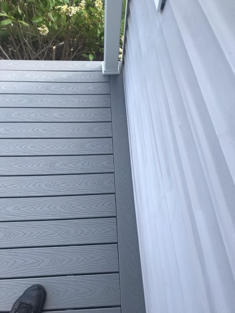 Gray composite deck and siding meet at corner, viewed from above.