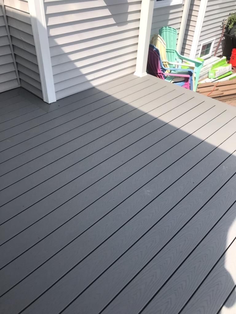 Gray composite deck with black grooves in sunlight.
