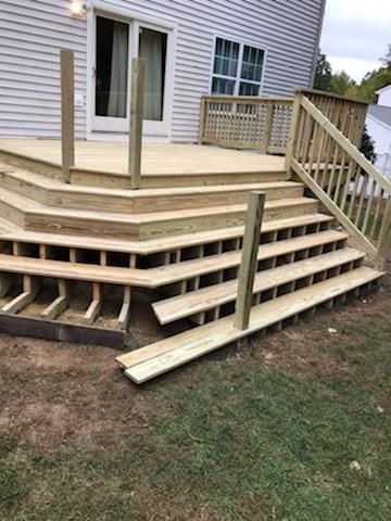 Wooden deck with multiple steps leading to a house, with unfinished railing and posts.