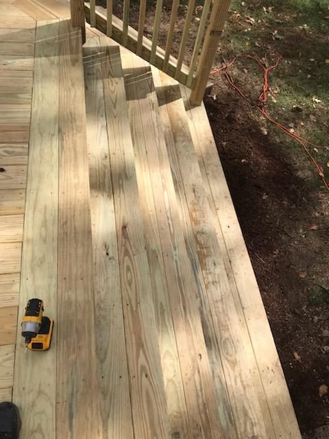 Newly built wooden deck and stairs; a yellow drill rests on the deck boards.