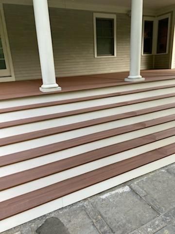 Front steps of a house with alternating brown and white treads, and white pillars supporting the porch.