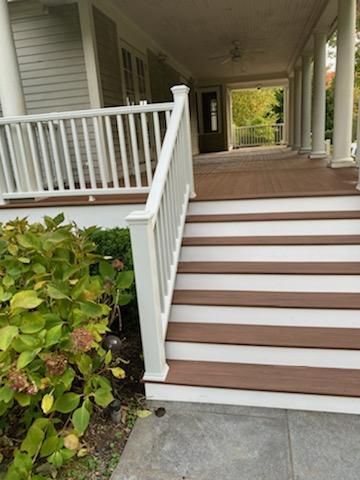 A set of brown and white stairs leading up to a covered porch with white columns.