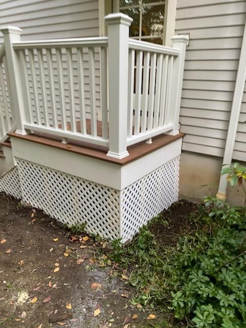 White deck with lattice skirting and railing, brown deck surface, and surrounding landscaping.