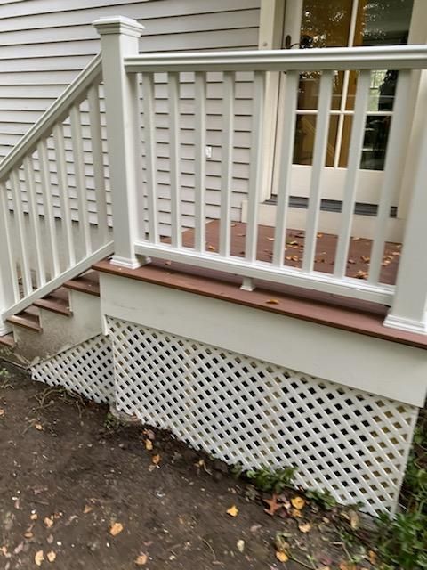 White porch with steps, lattice skirt, and railing; brown deck and trim.