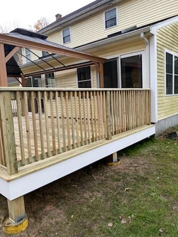 Wooden deck attached to a light yellow house with a covered patio.