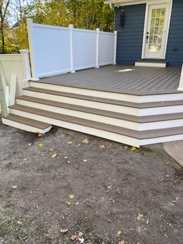 Composite deck with steps, white railing, and blue house exterior.