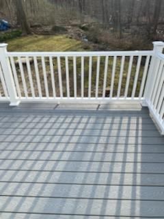 Gray deck with white railing, casting shadows in a sunny outdoor setting.
