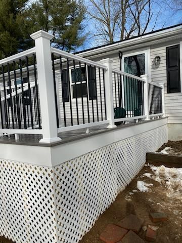 White deck with black railing and lattice siding on a house.