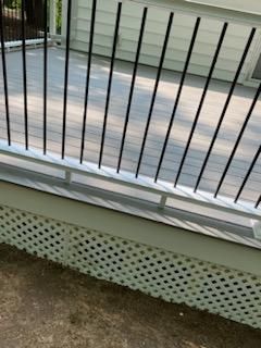 Deck with white railing, black vertical spindles, and lattice skirting.