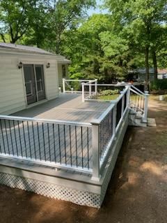 A gray composite deck with white railings and black balusters, attached to a white house with a sliding door.