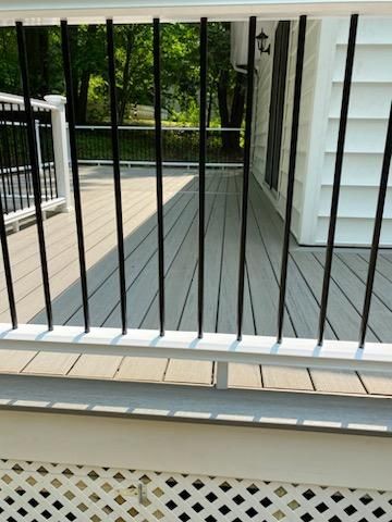 A deck with light gray composite decking, white railing and black metal balusters.