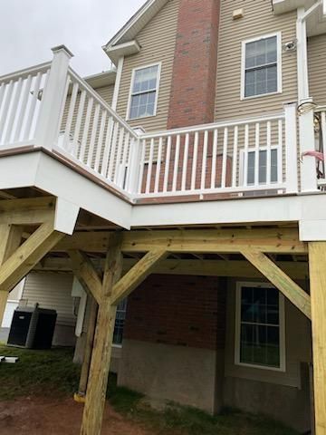 Wooden deck attached to a two-story beige house with white railing and support beams.