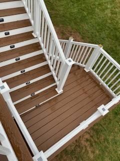 Wooden deck with white railings and built-in step lights, leading to a grassy yard.