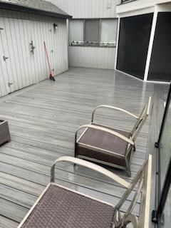 Two chairs on a gray deck with a shed and screened area.