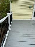 Gray wooden deck with black railing and yellow siding.