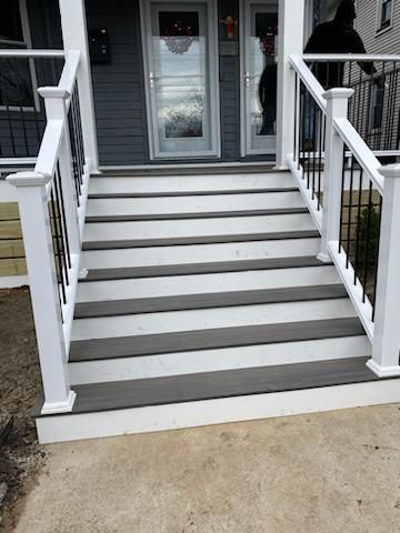 Gray and white outdoor steps leading to a front door with black iron railings, and a person is visible.
