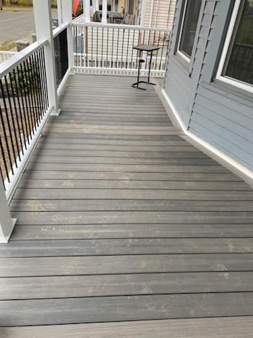 Gray wooden porch with white railings and a small table.
