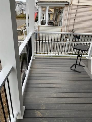 Gray composite deck with white posts and railings, black vertical bars, and a small black table.