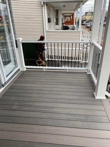 Grey composite deck with white railings and black spindles, person standing.
