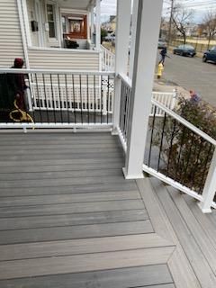 Gray composite deck with white railings and black spindles, viewed from street level.