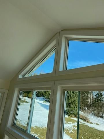 White-framed windows with a triangular top pane and a clear blue sky visible.