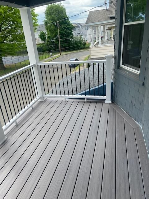 Gray composite deck with white railings and black spindles, overlooking a street.