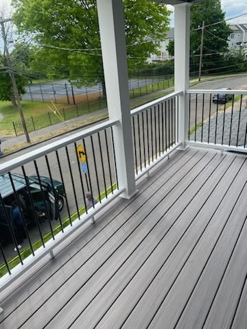 Gray composite deck with white railings and black vertical bars, overlooking a street.