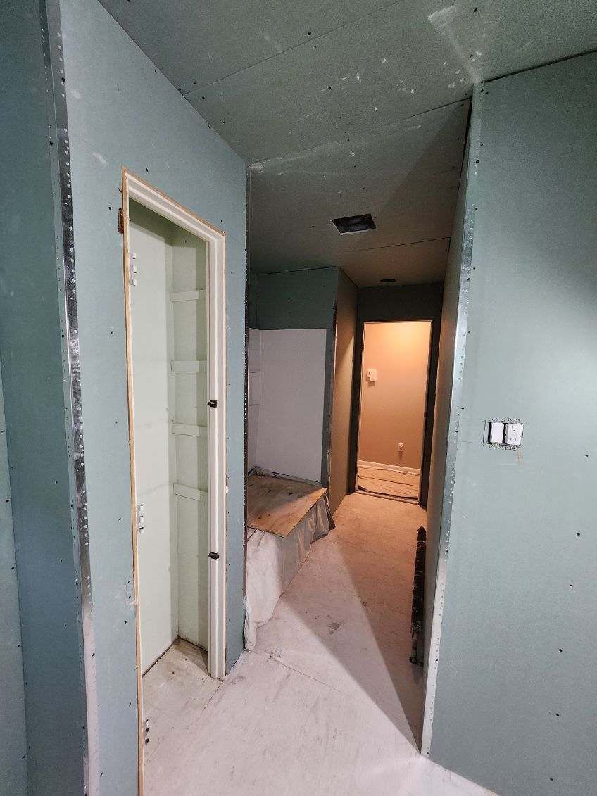 Construction of a hallway, with drywall, doors, and unfinished surfaces; interior.
