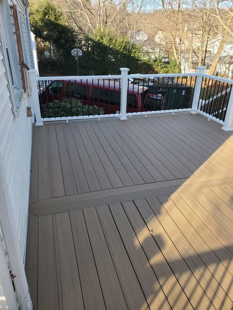 Brown composite deck with white railings, looking out at trees and houses.